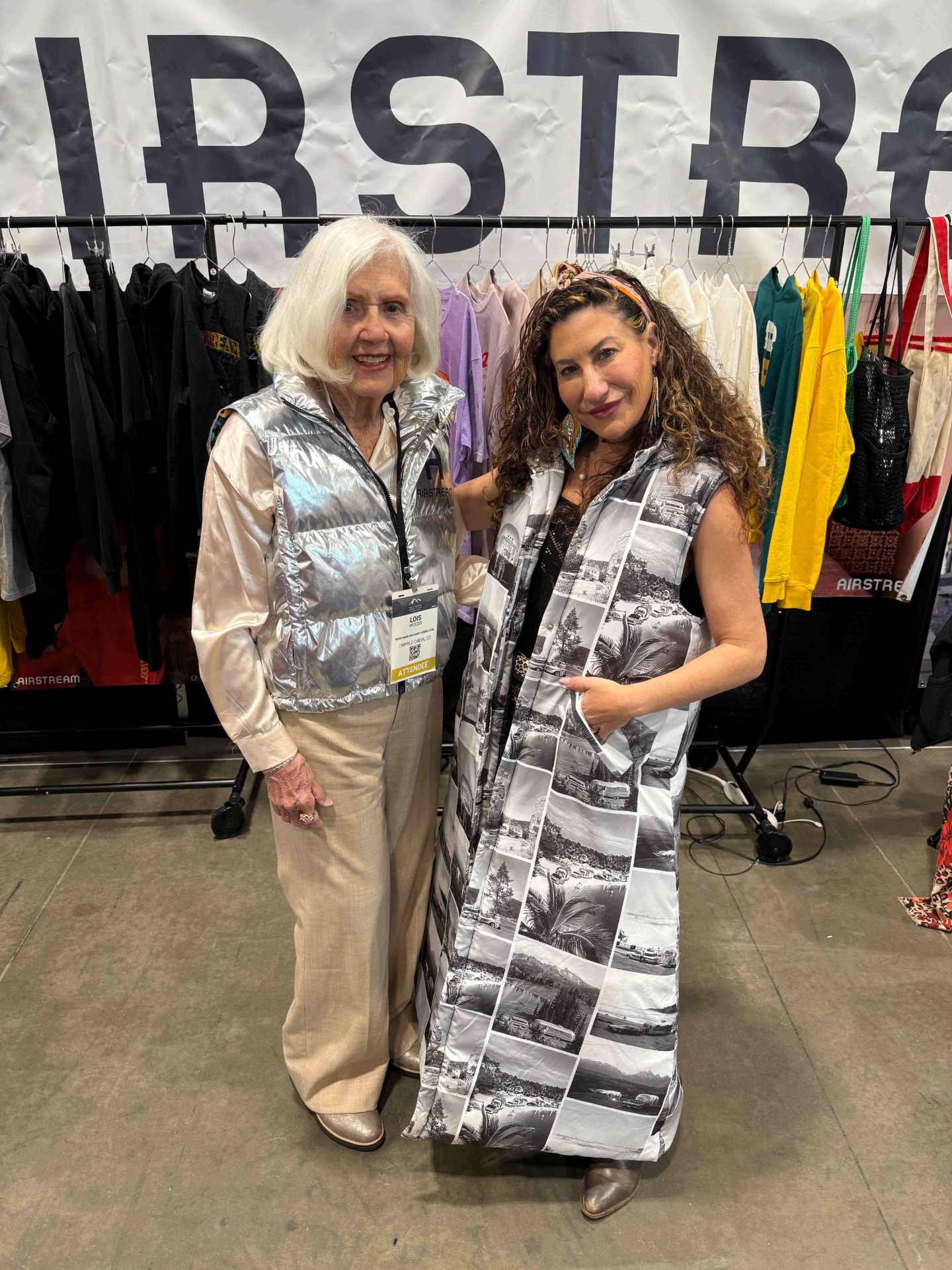 Two guests at the Airstream apparel showcase wearing a silver puffer vest and an archival-print long vest