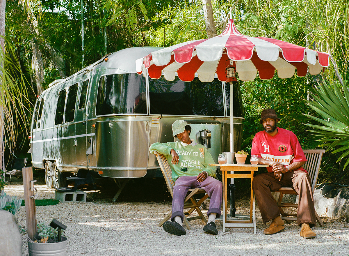Vintage Heavy models wearing Airstream capsule apparel beside a silver Airstream trailer
